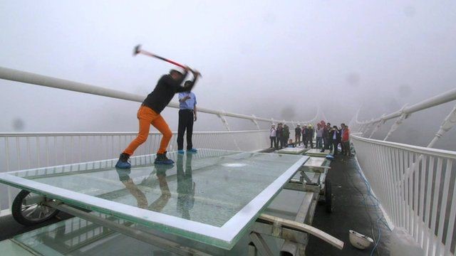 Phóng viên thử nghiệm đập tấm kính đáy cầu bằng búa tạ. Ảnh: BBC.
