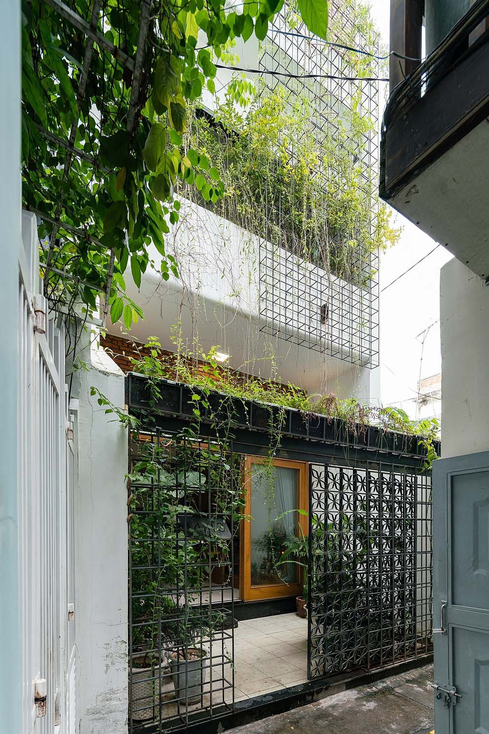 Mặt tiền công trình gây ấn tượng với cổng "hoa sắt", giàn leo và cây xanh trên nền tường trắng. Ảnh: Quang Trần.