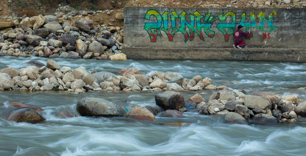 Hoạ sĩ Dũng Zunk bên một tác phẩm graffiti của mình.