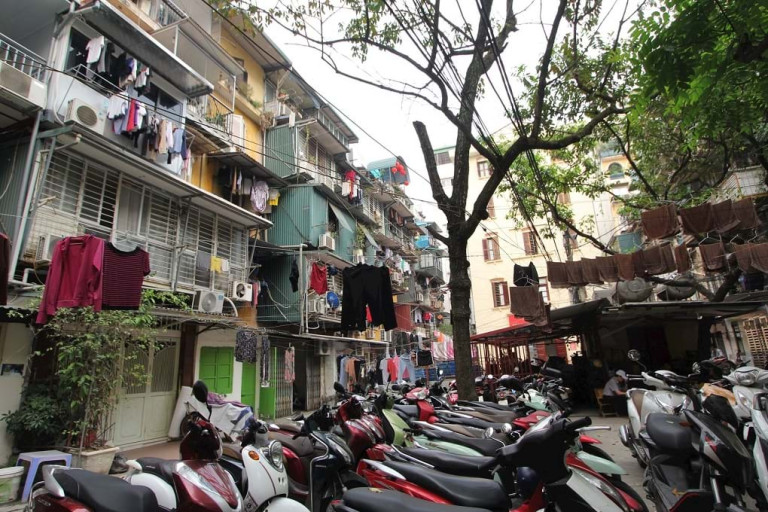 Khu tập thể Trần Quốc Toản có gần 100 hộ dân nhưng do diện tích các căn hộ khá khiêm tốn (dưới 30 m2) và khu phụ đối diện căn hộ khoảng 4 m2 nên hầu hết các hộ dân đều cơi nới thêm “chuồng cọp” đua ra không gian chung, khu vực sân chơi chung trở thành bãi để xe và nơi phơi quần áo, chăn màn của các hộ dân. Nguồn: Báo Đại Đoàn Kết